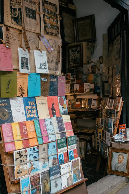 Free Explore a vintage bookstore entrance with a vibrant display of books and antique prints. Stock Photo