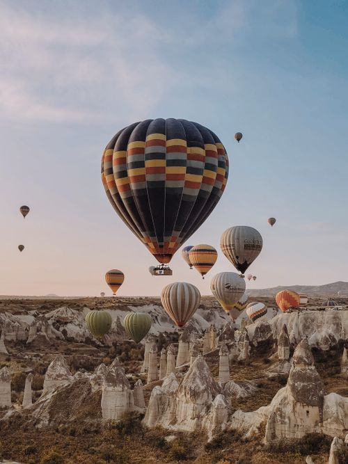 Free Dramatic view of colorful hot air balloons flying over Cappadocia's unique rock formations. Stock Photo