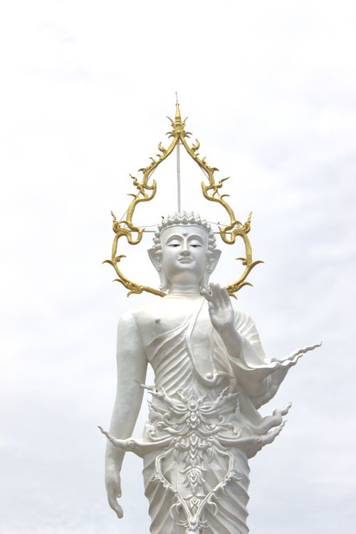 Free A stunning white Buddha statue with an ornate golden crown set against a serene sky. Stock Photo