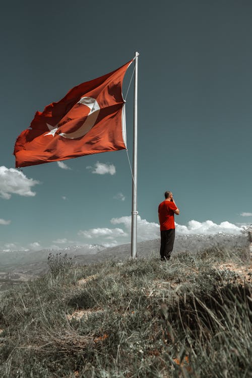 Man Standing near Turkish Flag on Hill