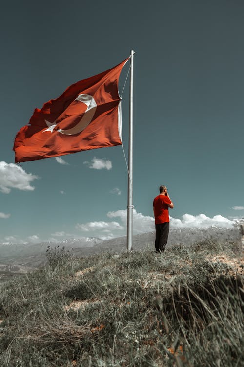 Man Standing near Turkish Flag on Hill