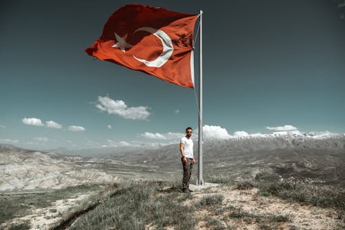 Man Standing under Turkish Flag on Hill