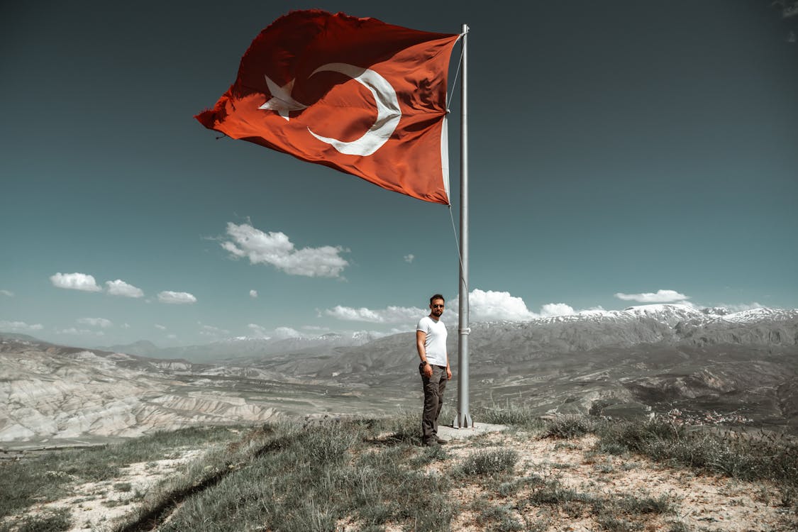 Man Standing under Turkish Flag on Hill