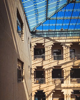 A sunlit industrial interior with a striking glass ceiling casting shadows.