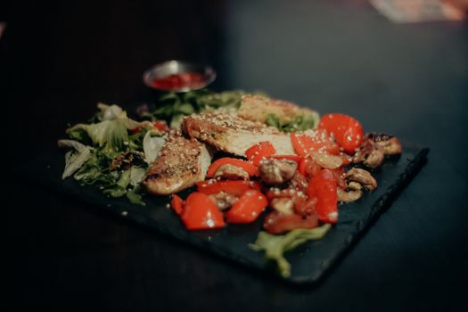 Savor a savory dish of grilled chicken with vibrant peppers, mushrooms, and greens.
