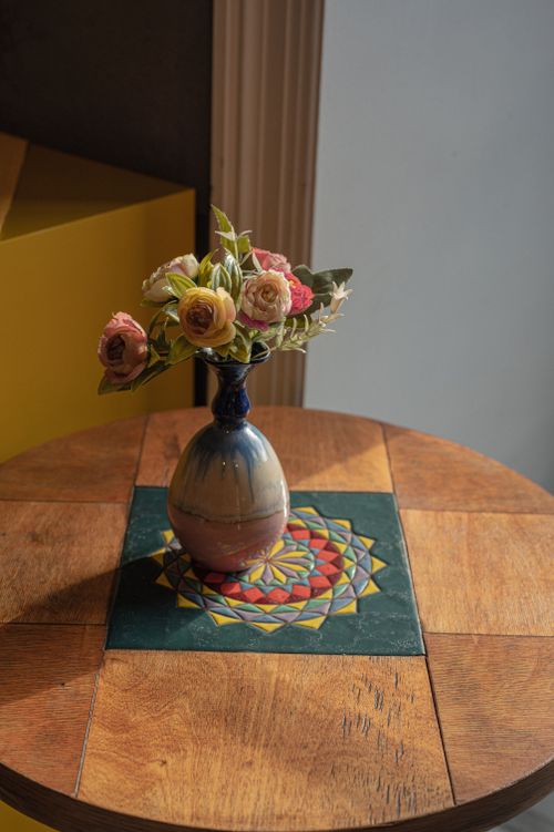 Free Elegant vintage vase with flowers on a geometric patterned wooden table. Stock Photo