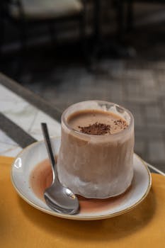 Chilled cappuccino served in a frozen glass with chocolate flakes on top at an outdoor cafe setting.