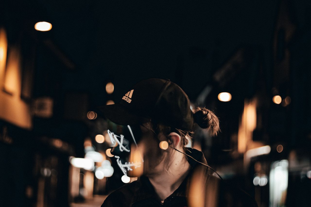 a person wearing a cap in a dimly lit urban setting at night with crea
