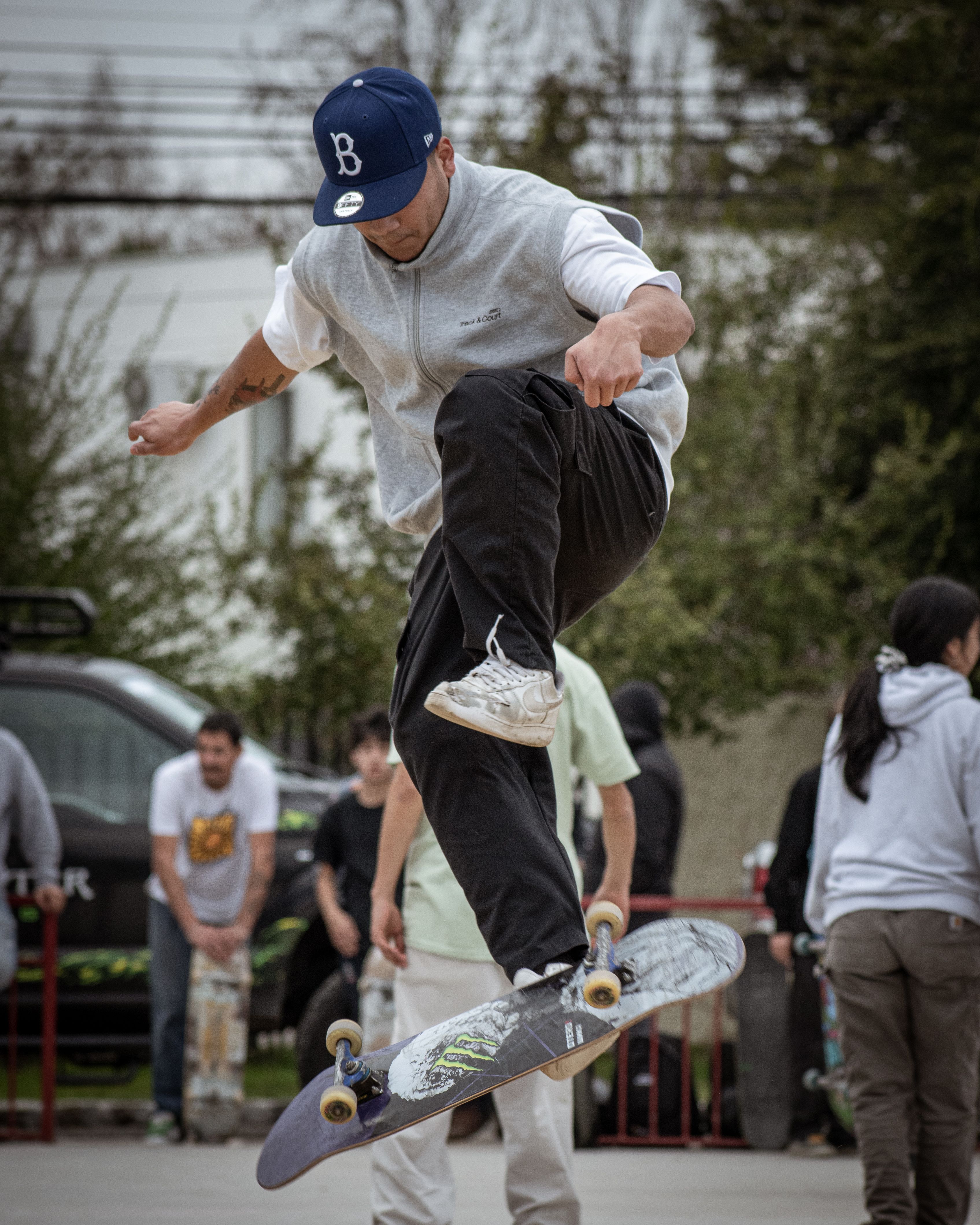 A skateboarder executes a mid-air flip trick in a lively skate park with spectators.. skateboarder, executes, flip