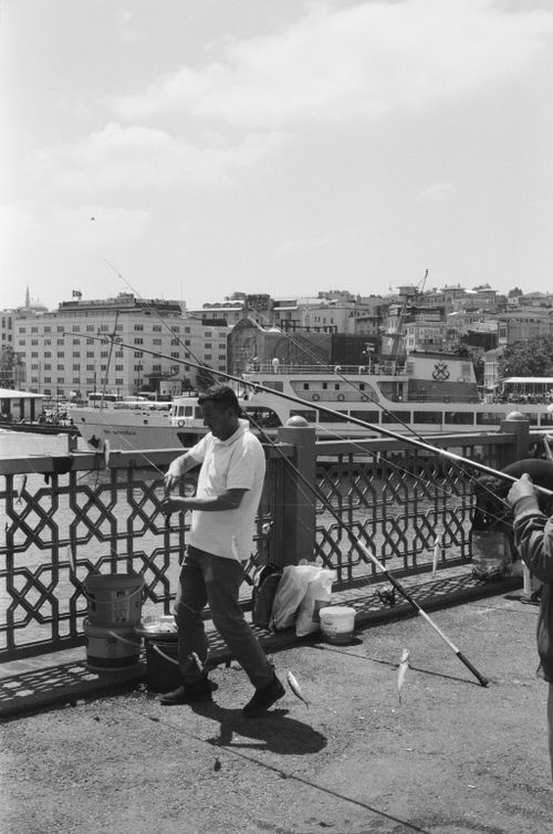 Free Men fishing on the historic Galata Bridge in Istanbul, capturing urban life and leisure. Stock Photo
