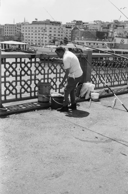 Free Black and white photo of a fisherman on Galata Bridge in İstanbul, capturing urban life. Stock Photo