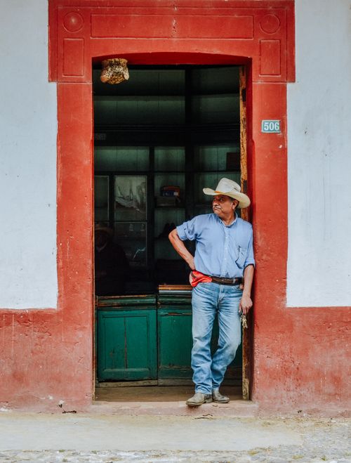 Free Elderly man stands in a doorway in Cuetzalan, Mexico, wearing a hat and jeans. Stock Photo