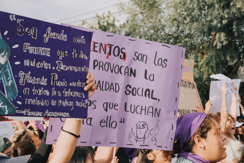 Mujeres sosteniendo carteles de protesta durante una demostración de justicia social al aire libre.