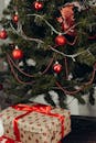 装饰着红色饰品的圣诞树下，摆放着包装好的礼物，洋溢着浓浓的节日气氛