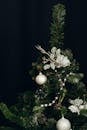 深色背景上，一棵装饰着银色花环、饰品和花卉的圣诞树特写镜头