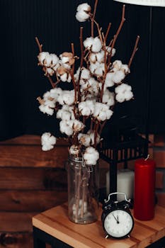 玻璃罐里装着优雅的棉花花束，木桌上有时钟和蜡烛