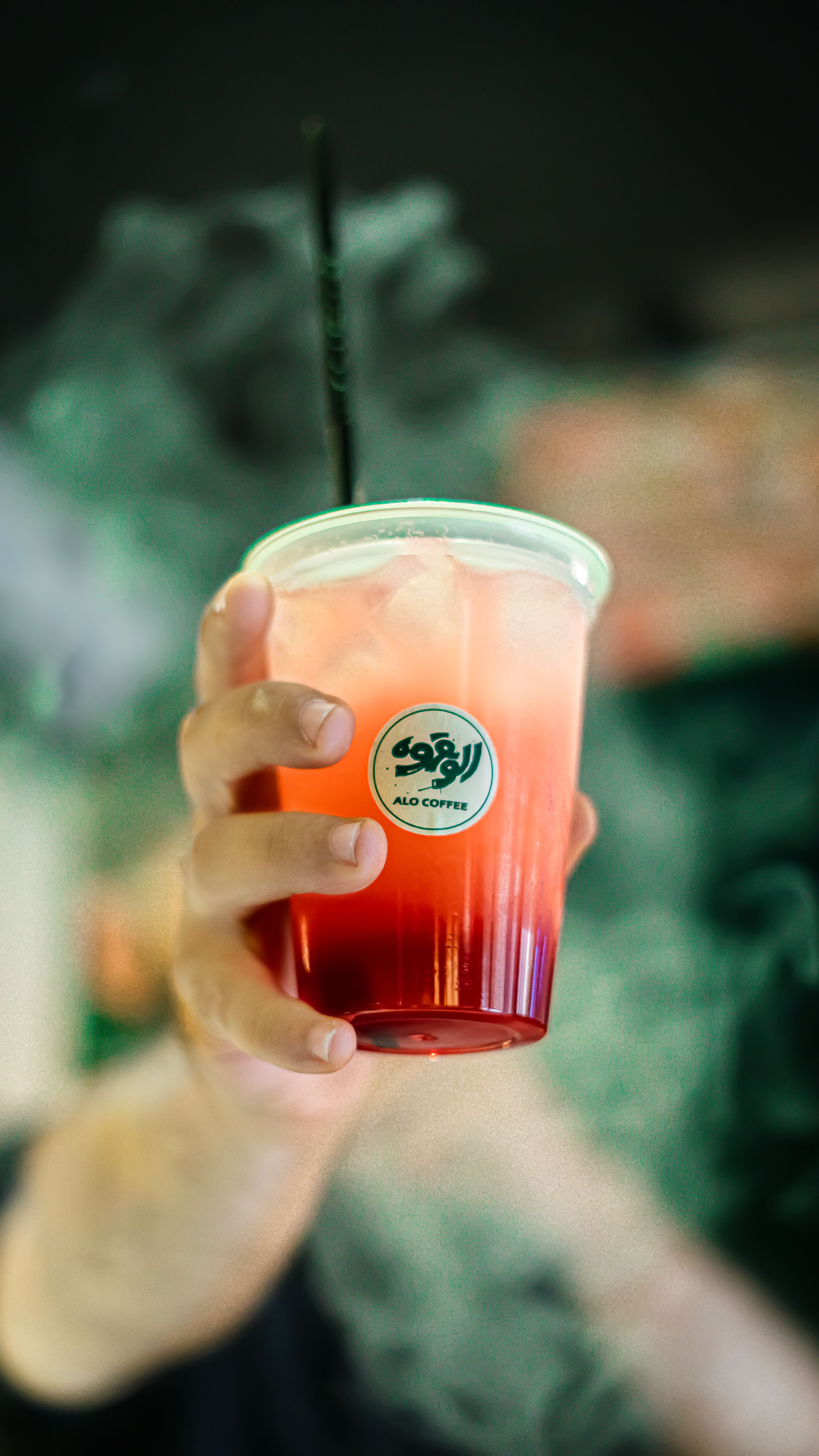 Hand holding a refreshing iced tea in a clear plastic cup with smoke background.