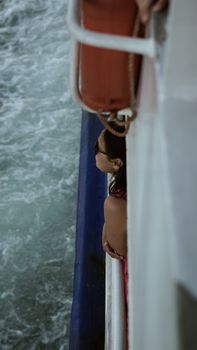 Woman enjoying a serene boat ride, gazing at the sea with a summer vibe.