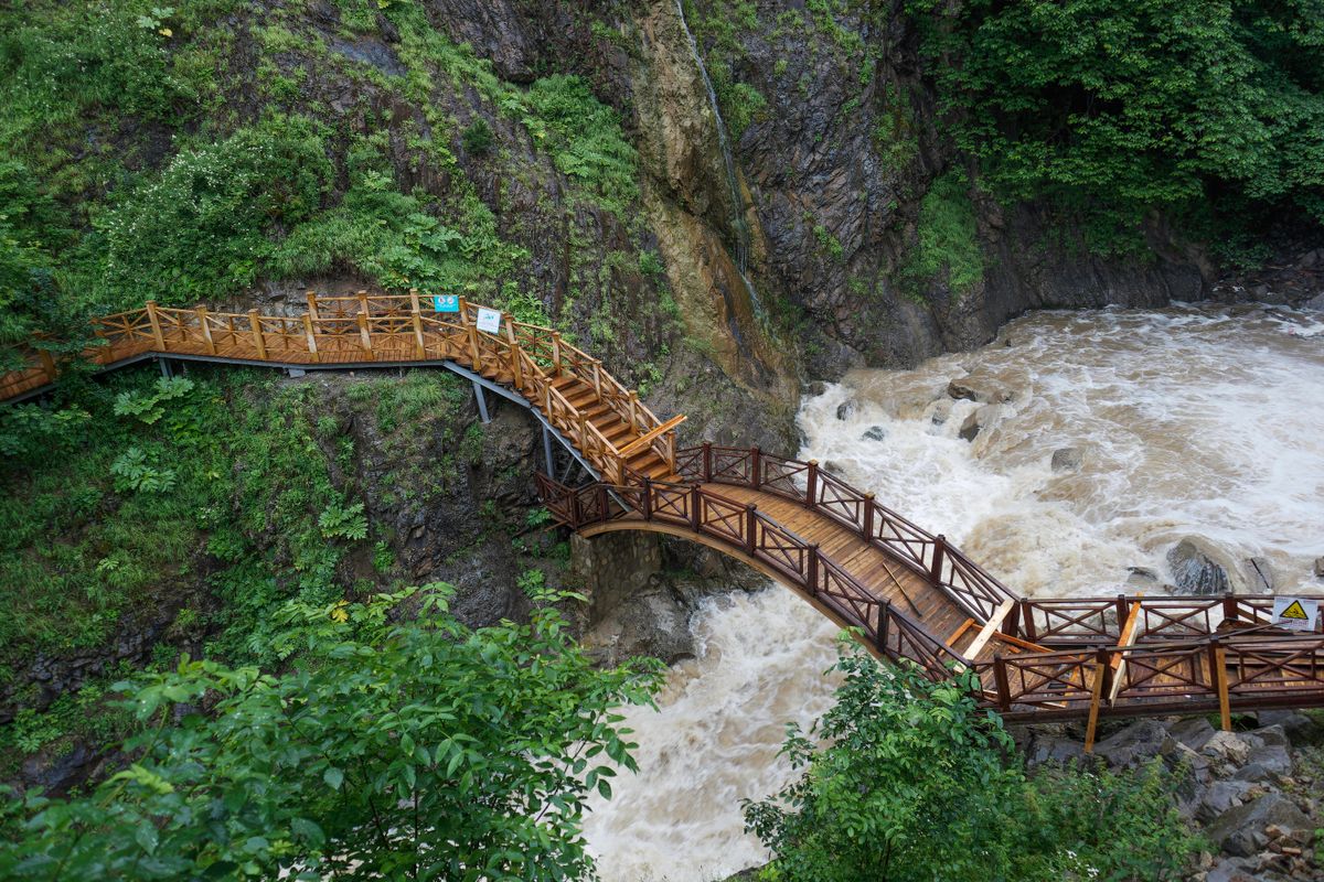 Vedere aeriană cu o pasarelă de lemn peste un râu de munte