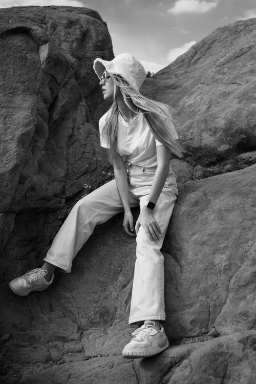 Free Stylish woman in a hat and pants posing on rocky terrain in Agua Dulce. Stock Photo