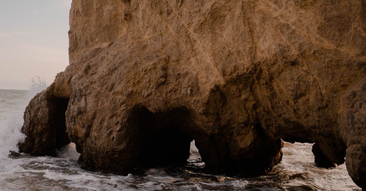 Sea Foam under Rock Formation · Free Stock Photo