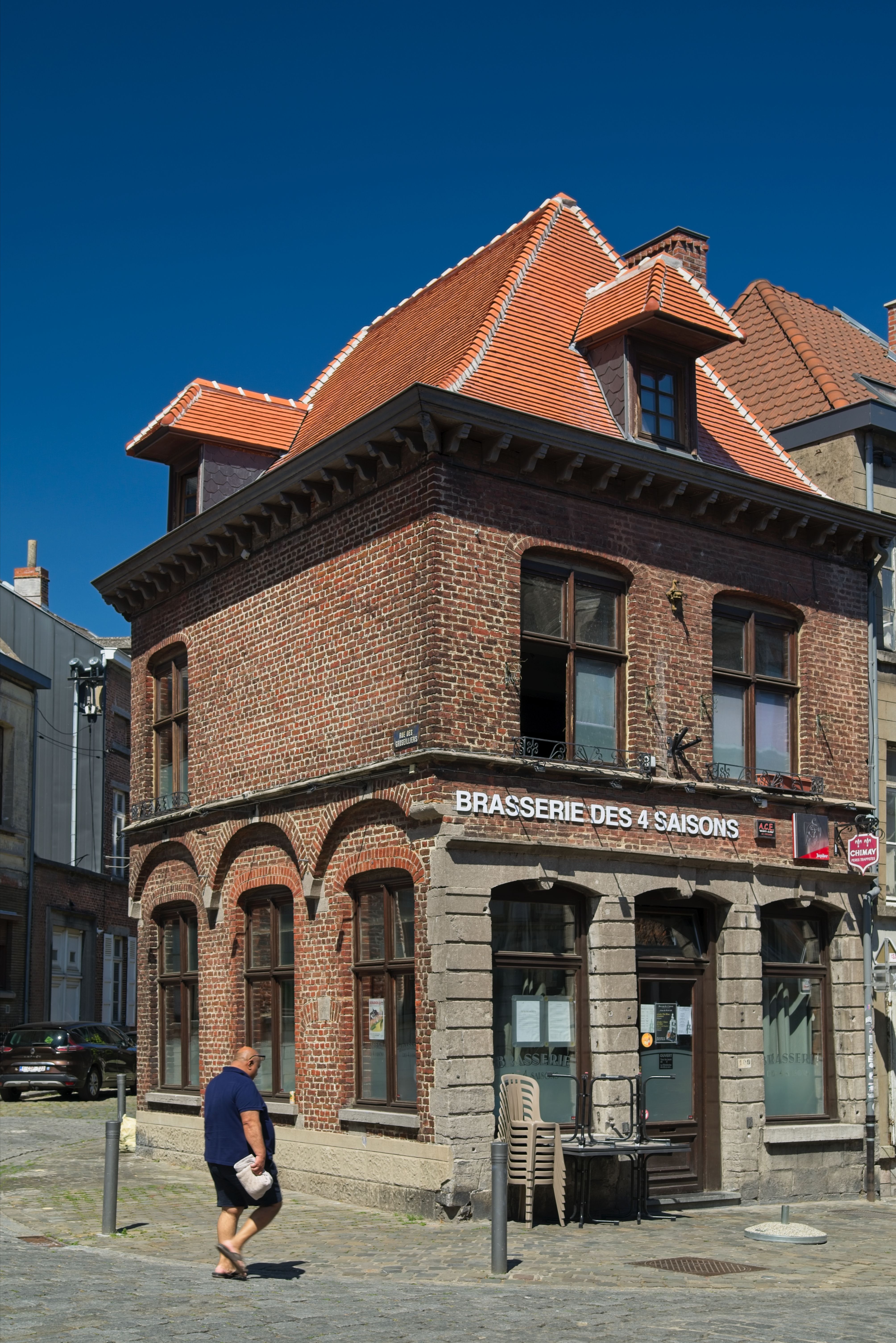 A historic brick brasserie on a sunny street corner in a French town.