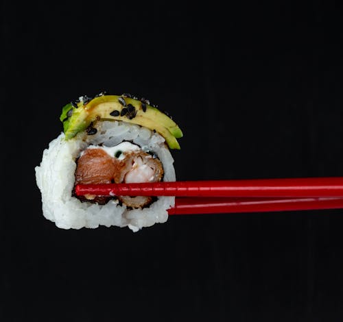 Close-up of Sushi between Chopsticks