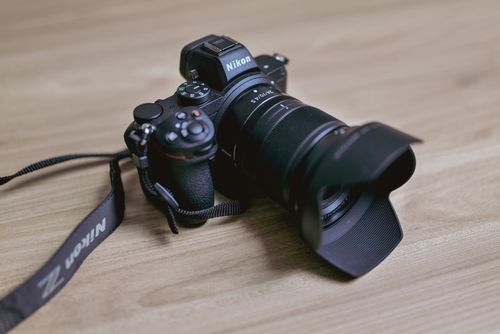 Free Close-up view of a DSLR camera with a zoom lens on a wooden background, ideal for photography themes. Stock Photo