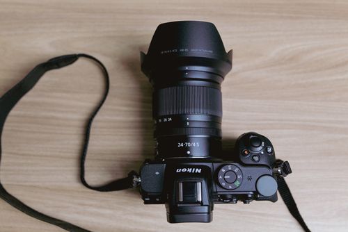 Free Flat lay of a professional digital camera with a lens on a wooden table surface. Stock Photo