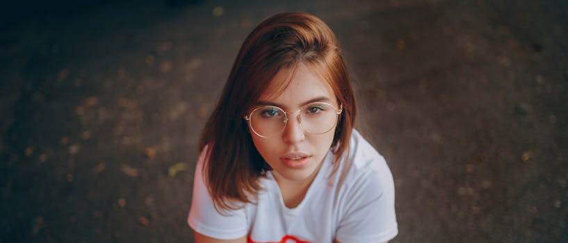 户外，一名戴眼镜的年轻女子若有所思地抬起头