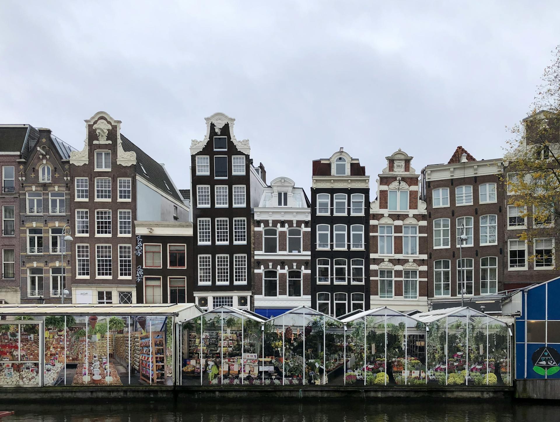 Iconic canal houses and floating Flower Market in Amsterdam, Holland reflect Dutch charm.