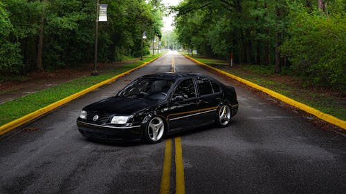 Free Tuned Volkswagen Jetta on Road in Forest Stock Photo