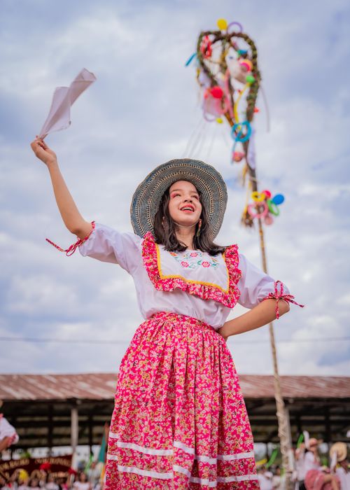 Free Smiling woman in traditional dress waving a ribbon at a vibrant cultural festival. Stock Photo