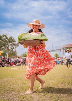 Woman in colorful dress celebrates festival in Rioja, Peru, holding a large tray with joy.