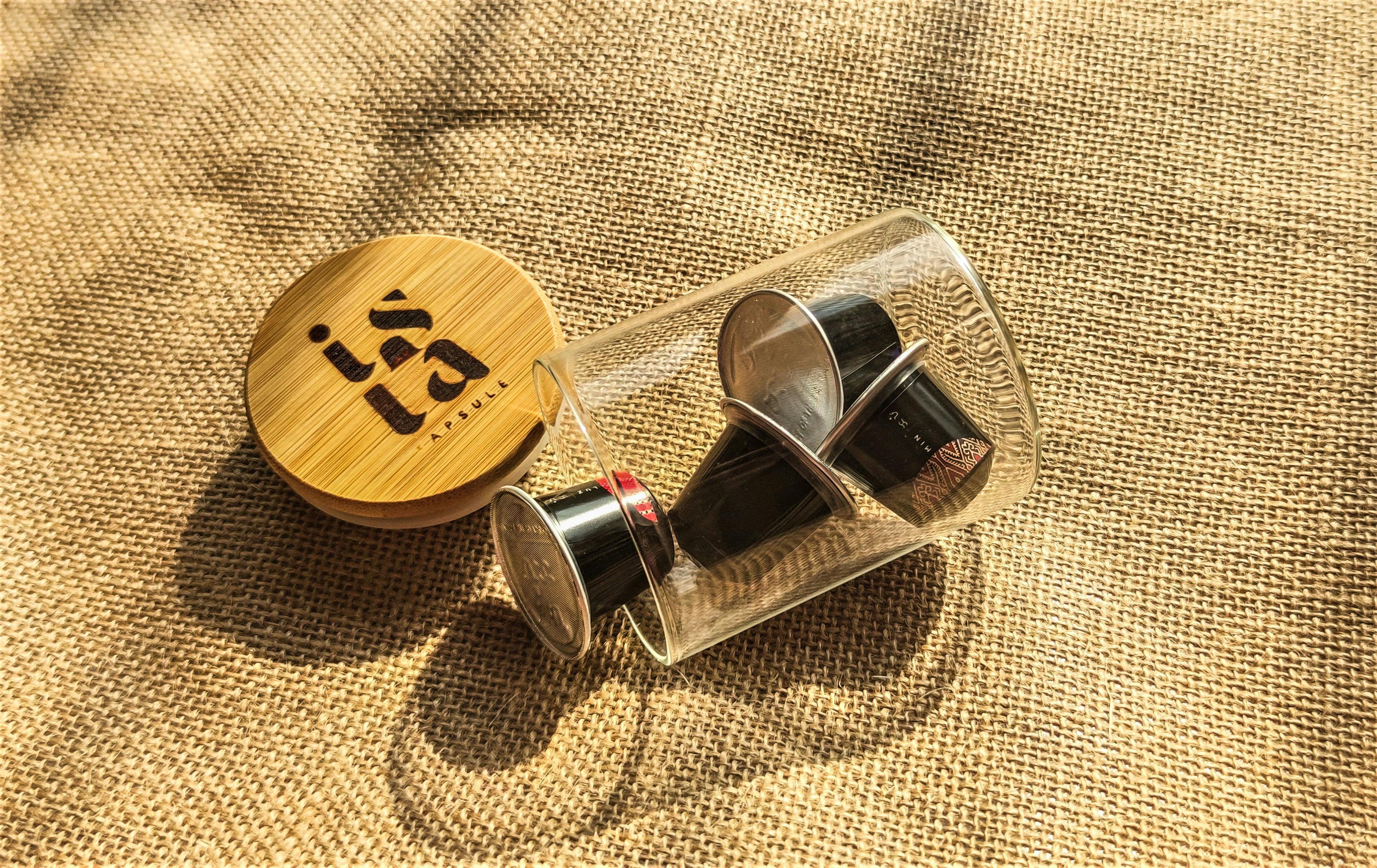 Free Reusable coffee capsule set inside a glass jar with bamboo lid on burlap. Eco-friendly concept. Stock Photo
