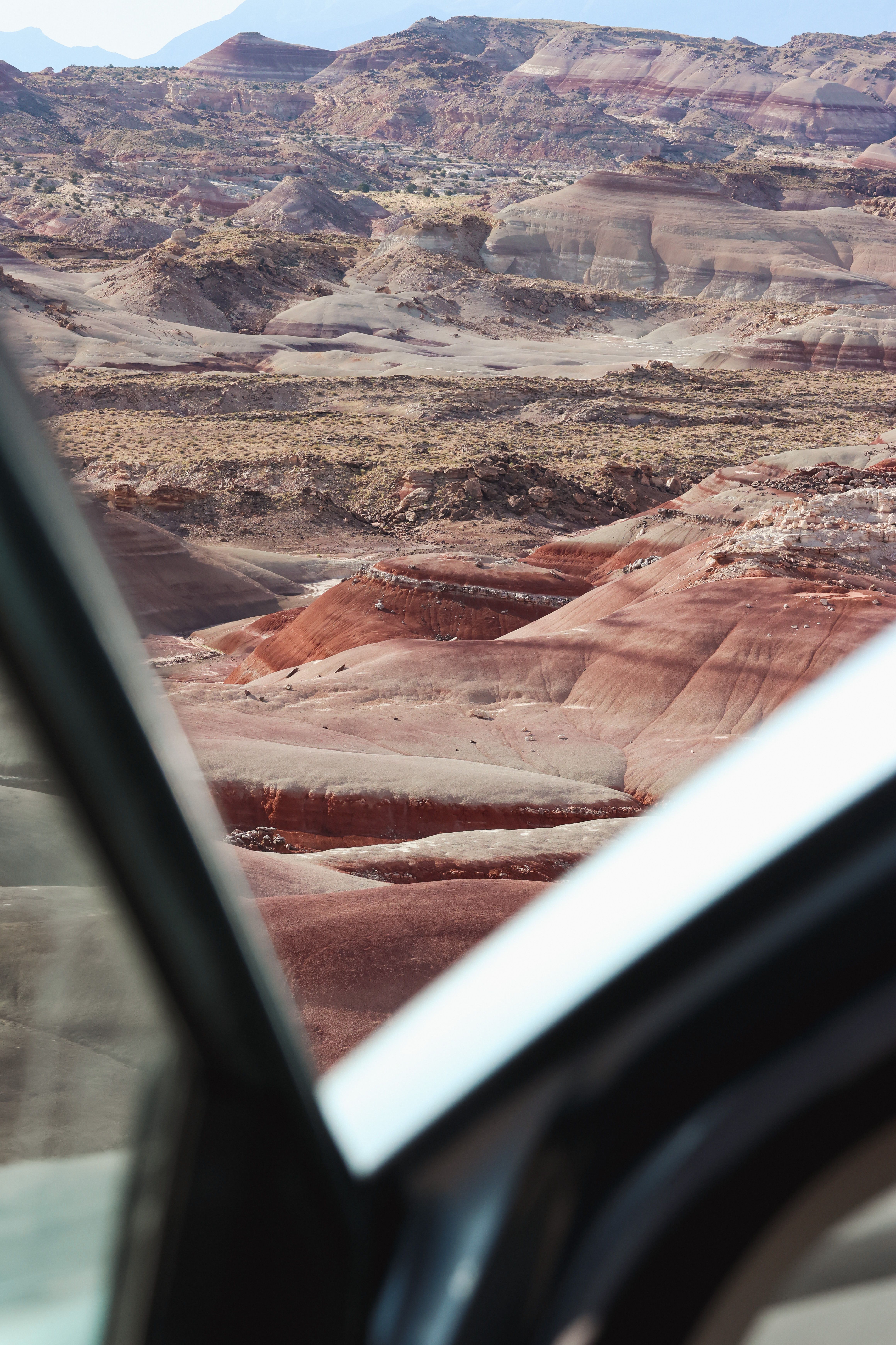 View of Utah's dramatic desert canyons through a car window, showcasing the rugged and colorful terrain.