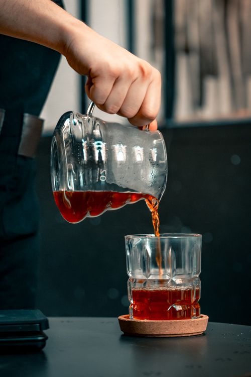 Free A person pouring tea into a glass in a modern café setting in Adana, Turkey. Stock Photo