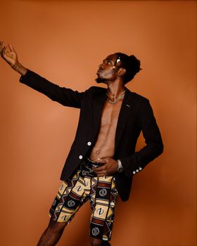 Portrait of a fashionable young man posing confidently against an orange background in a stylish suit.