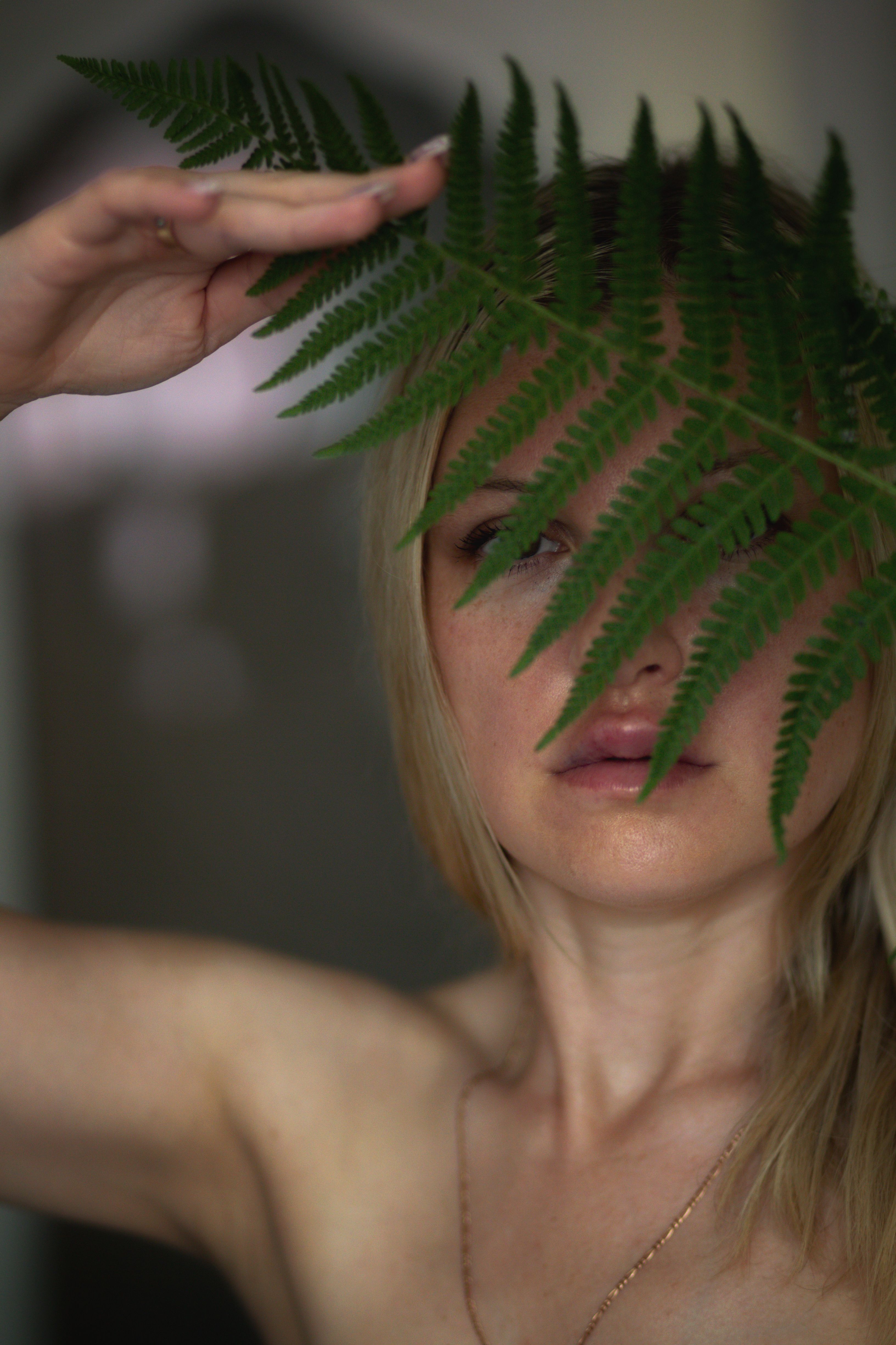 A woman with a fern leaf covering her face · Free Stock Photo