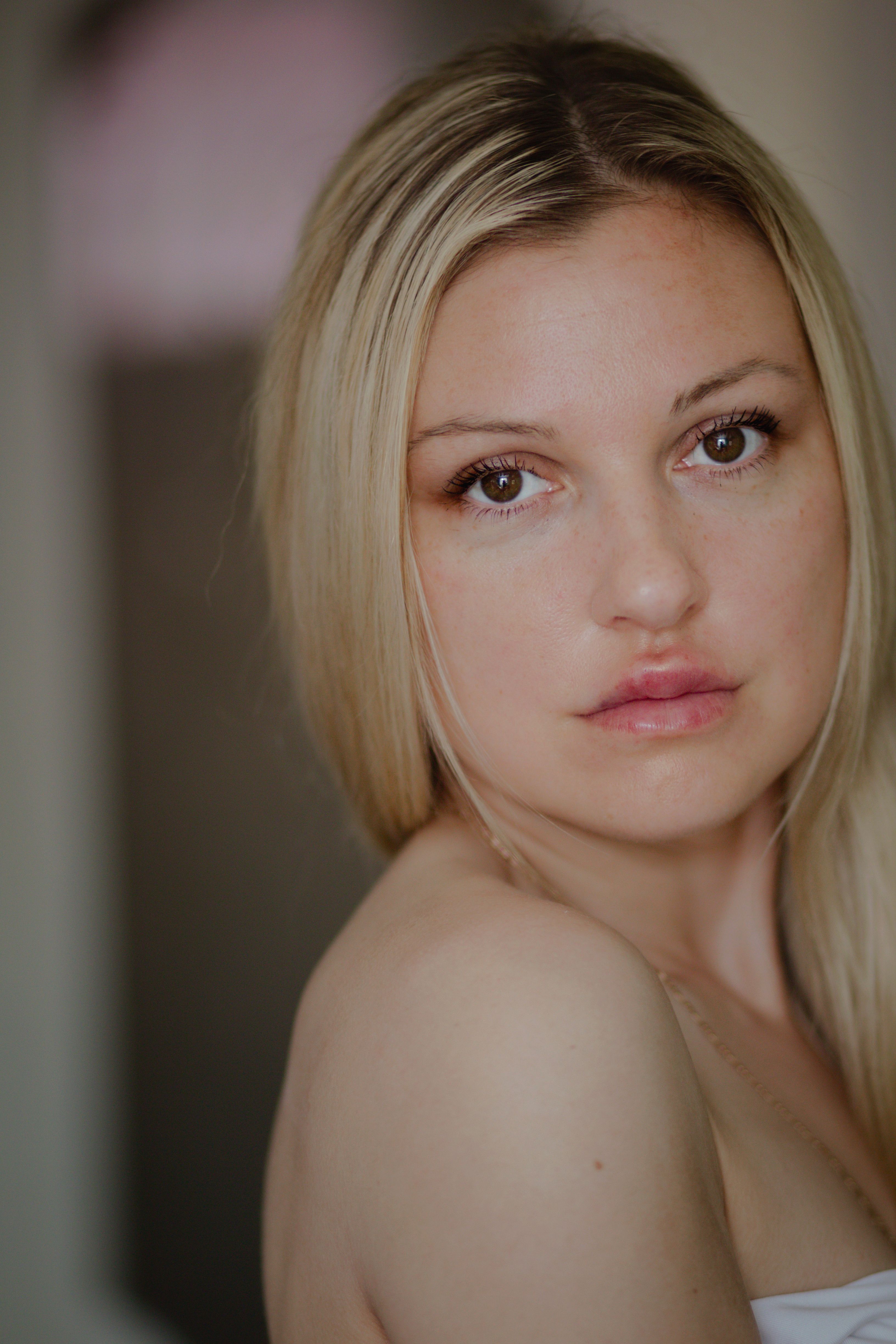 A close-up studio portrait of a young blonde woman with elegant makeup and hairstyle.