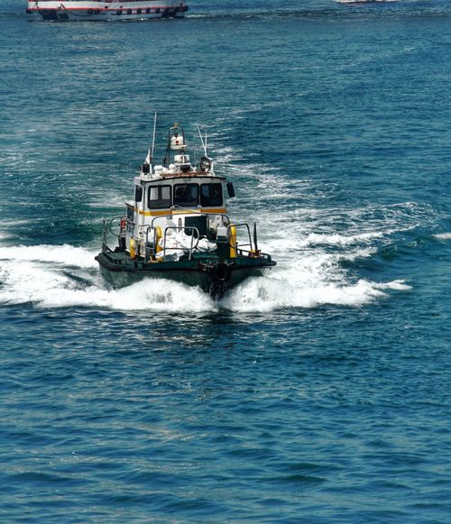 Free A small boat cruises through the ocean, leaving waves in its wake on a bright day. Stock Photo