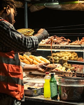 A street food vendor preparing and serving snacks at a bustling night market in Colombo, Sri Lanka.