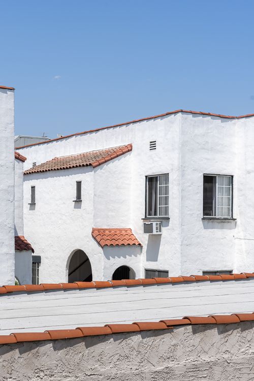Free White stucco building with terracotta roof under a clear blue sky, showcasing Mediterranean architecture. Stock Photo