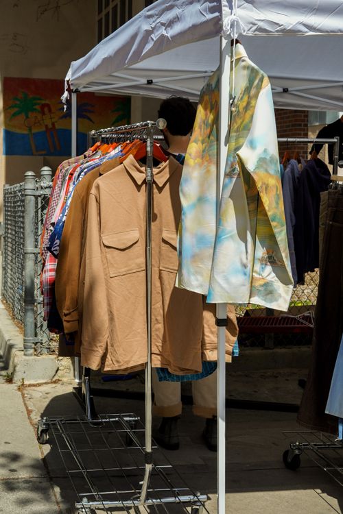 Free Outdoor market showcasing vintage clothes on racks under a sunny sky. Stock Photo