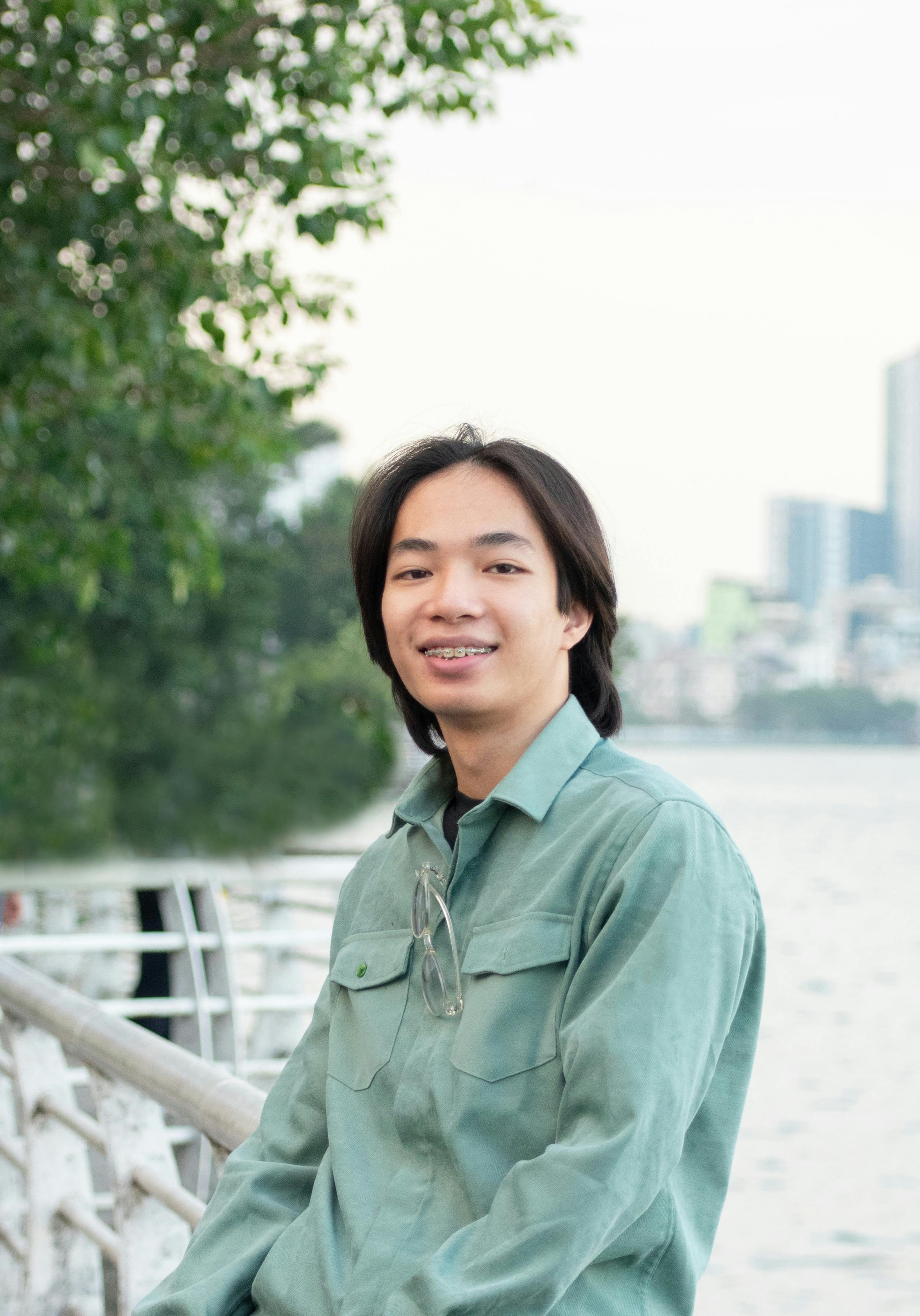 Smiling adult by the river with cityscape background.