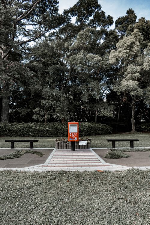 Free Peaceful park in Toyohashi featuring a red vending machine and symmetrical benches. Stock Photo