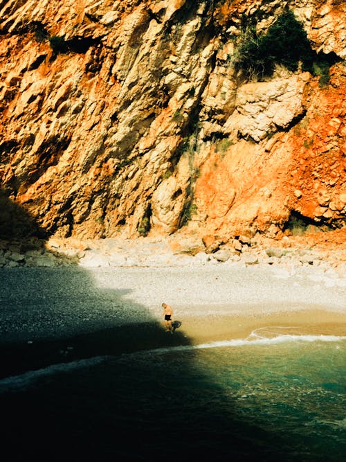 Man on Beach under Rocks