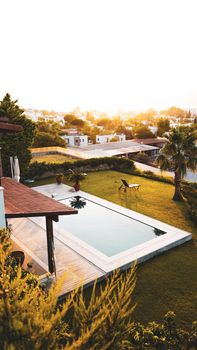 Stunning aerial image of a luxurious backyard with a swimming pool during a warm sunset.