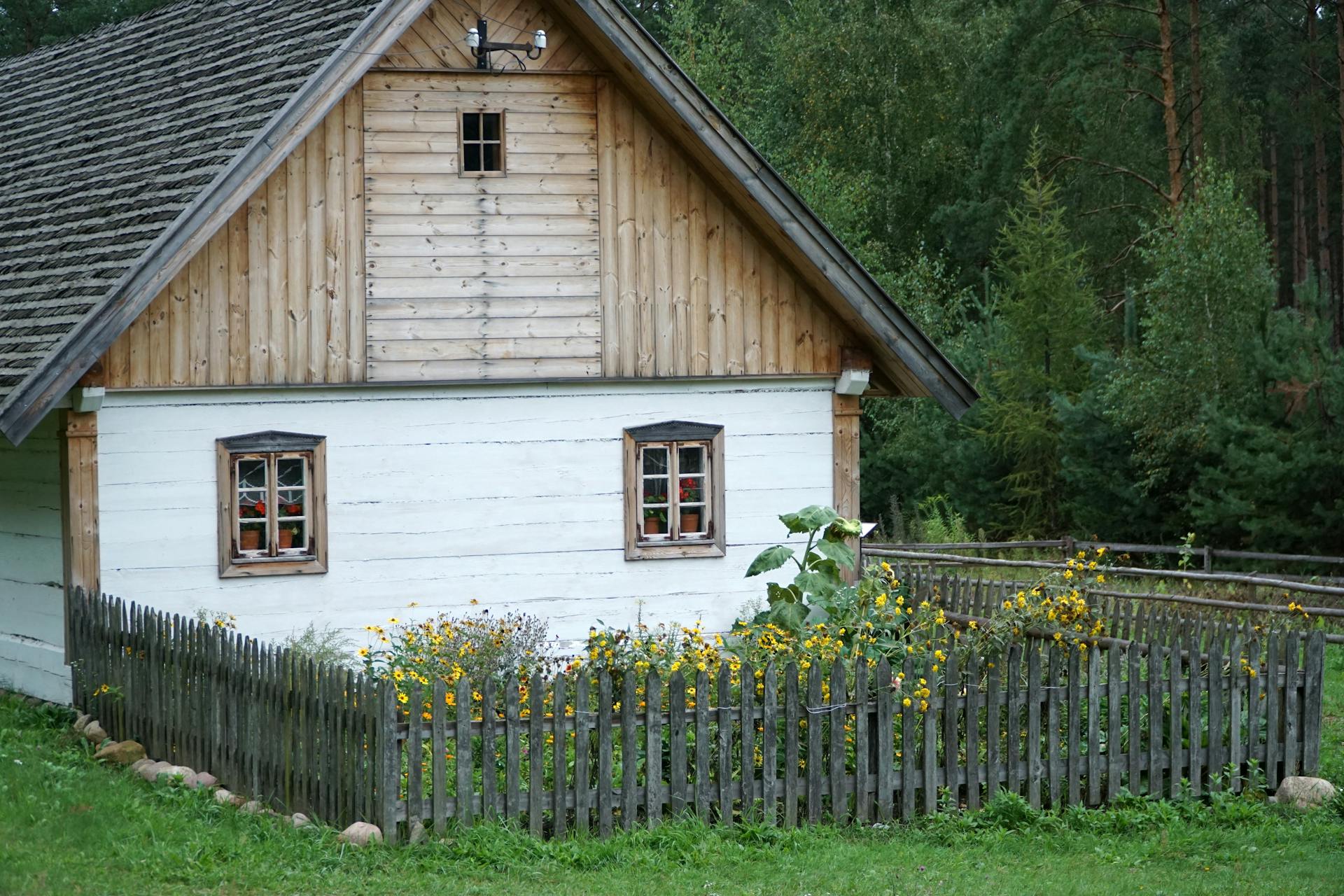 A small wooden house with a fence and flowers