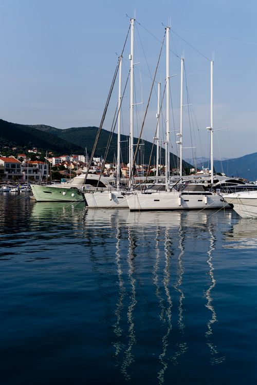 Free Sailboats and yachts moored at a scenic marina under clear blue skies, reflecting on calm waters. Stock Photo